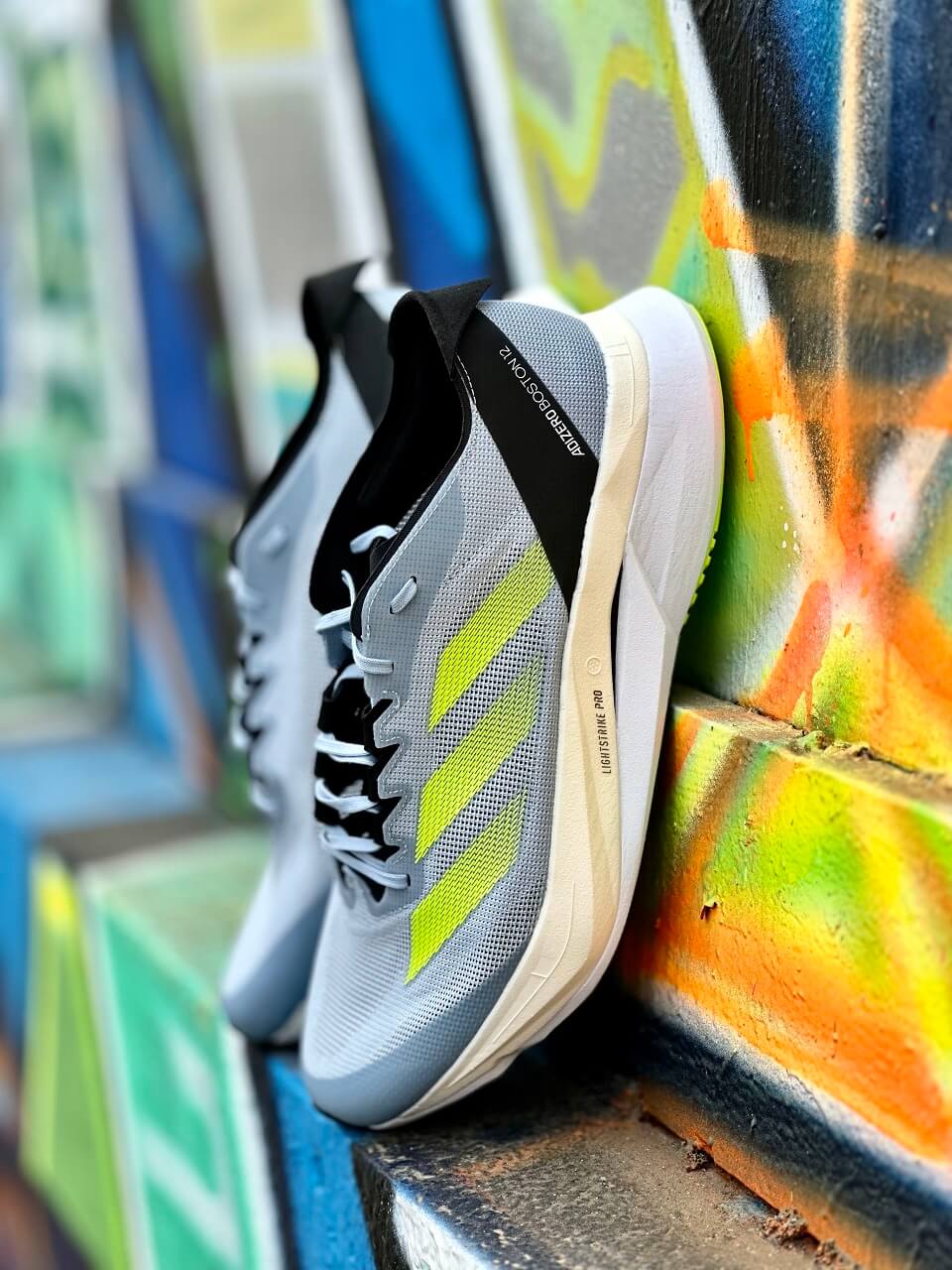 adidas running shoes propped against a graffiti wall